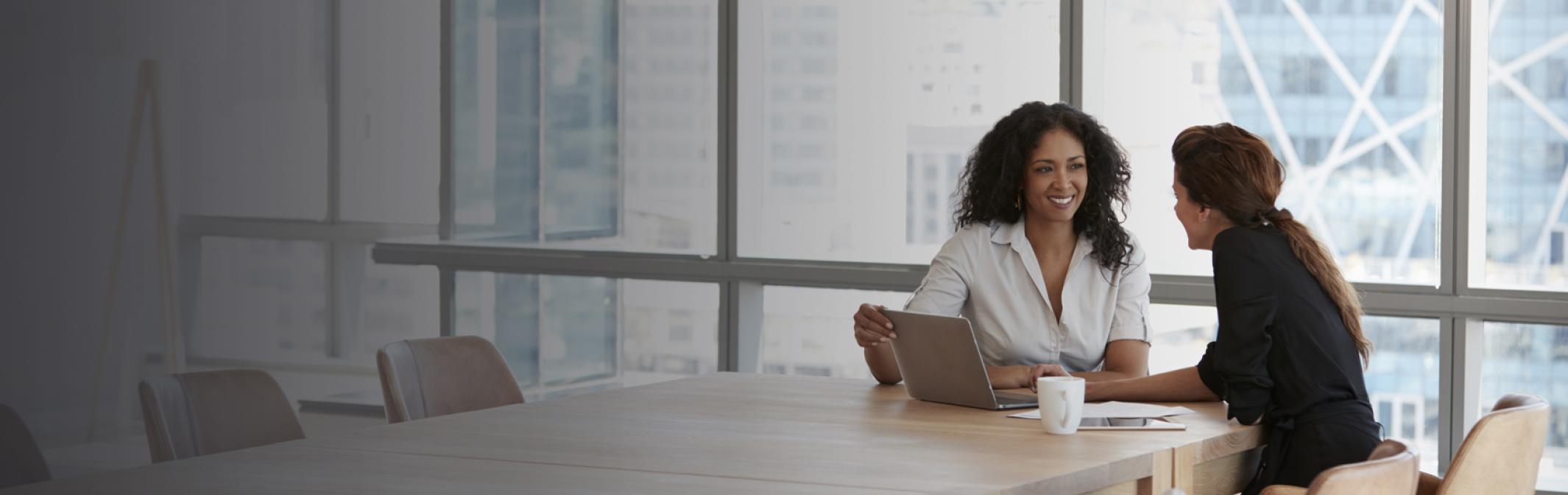 Two women discussing business at conference table