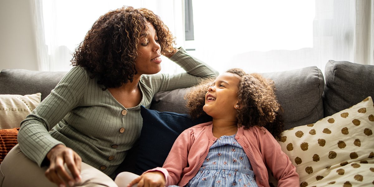 Mother and daughter seated and smiling at each other