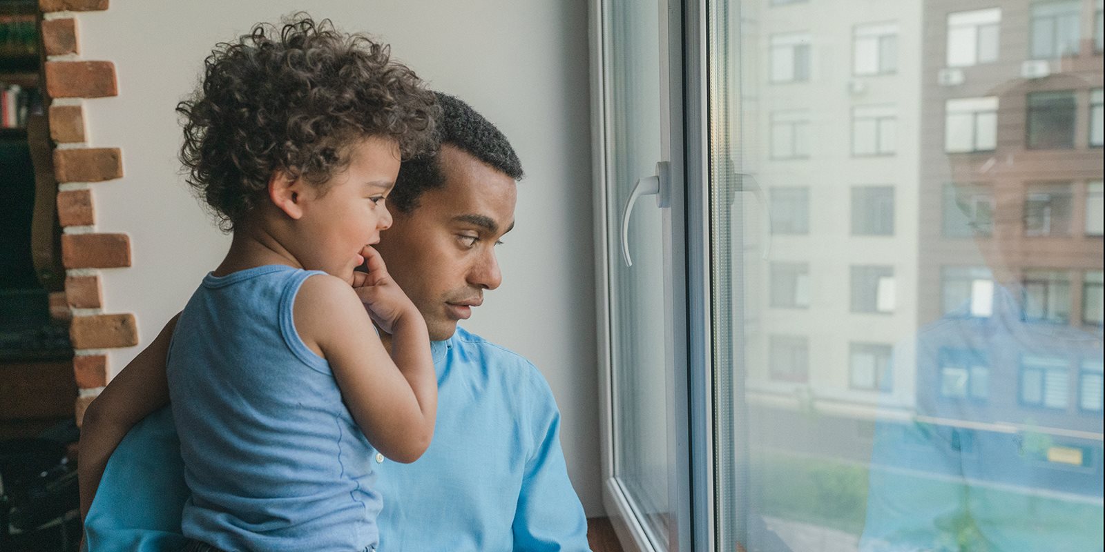 Man holding boy and looking out a window